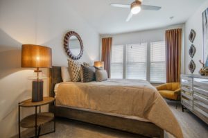 Carpeted bedroom with ceiling fan and large windows